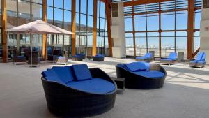 卡拉马Alto del Sol Calama的大楼内带蓝色椅子和遮阳伞的大堂