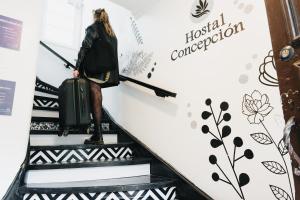康塞普西翁Apart hotel de Hostal Concepción的带着手提箱走下自动扶梯的女人