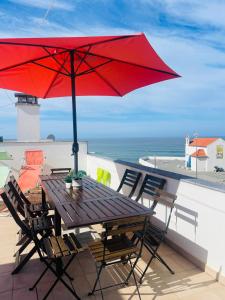 赞布热拉-杜马尔Sunset Beach House的阳台上配有带红伞的木桌