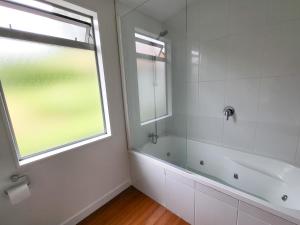 奥克兰Inner City Sunny Bedroom的带淋浴和浴缸的浴室以及窗户。