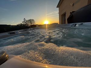 阿姆博斯Maison chaleureuse tout confort的按摩浴缸,背面是日落