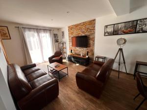 阿姆博斯Maison chaleureuse tout confort的客厅配有皮革家具和砖墙