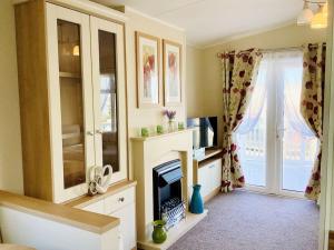 PorchfieldIdyllic mobile home in beautiful surroundings的客厅设有壁炉和窗户。