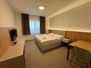 克伦特尼采Comfort Pálava, Penzion & Restaurant的配有一张床和一张书桌的酒店客房