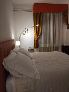 斯坎诺Bed & Breakfast Costanza4的一间卧室配有带白色枕头和灯的床