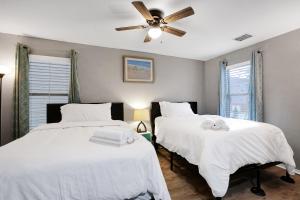 圣安东尼奥Tranquility - A Birdy Vacation Rental的卧室内的两张床,配有白色床单和吊扇