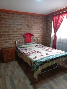 奥塔瓦洛Cozy cabin in the countryside Otavalo Learning的砖墙前的卧室配有一张床