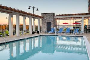 阿尔科Home2 Suites By Hilton Alcoa Knoxville Airport的一个带蓝色椅子和桌子的游泳池