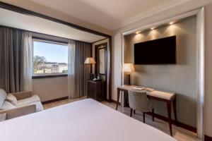 拉科鲁尼亚NH Collection A Coruña Finisterre的酒店客房配有一张床、一张书桌和一台电视。