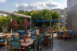 卢萨卡卢萨卡丽笙酒店的一间设有桌椅的餐厅,种植了棕榈树