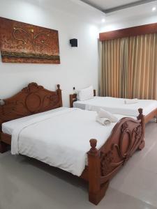吉利特拉旺安松树别墅酒店的配有白色床单的酒店客房内的两张床