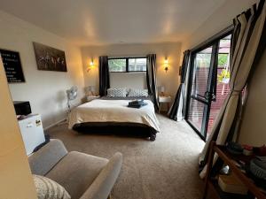 汉密尔顿Dinsdale oasis and private spa pool的一间卧室配有一张床、一张沙发和窗户。