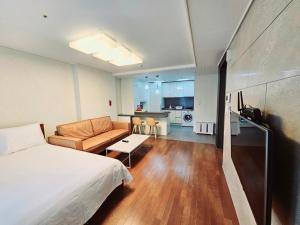 釜山Jeoung's House的一间卧室配有一张床和一张沙发,还设有一间厨房