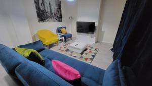 伦敦Garland Modern Close To Station 3 Bedroom City Apartment的客厅配有蓝色的沙发和黄色的椅子