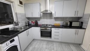 伦敦Garland Modern Close To Station 3 Bedroom City Apartment的厨房配有白色橱柜、水槽和炉灶。