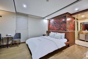首尔Flower Hotel的卧室配有一张白色大床和一张书桌