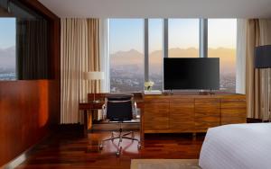 阿拉木图阿拉木图丽思卡尔顿酒店 的酒店客房设有电视和带椅子的书桌