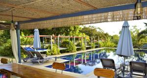 白马市Villa 'The Blue House' - Qbungalows的庭院设有带椅子和遮阳伞的游泳池。