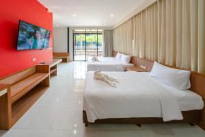 Ban Nong Chap TaoNongnooch Garden Pattaya Resort的红色墙壁的客房内的两张床