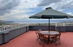 纳库鲁Naka Executive Suites With Balcony, Amazing Lake Nakuru View, GYM的屋顶上配有遮阳伞的桌椅