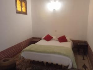 斯库拉达累斯萨拉姆酒店的一间卧室配有一张带两个红色枕头的床