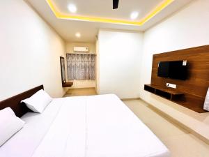 普杰Hotel Kutch Palace的卧室配有一张白色大床和电视。