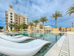 迪拜Trophy Twinkle Twine Jumeriah Retreat Suites的一个带白色椅子和棕榈树的游泳池