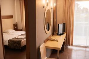 锡德Akalia Suite Hotel & SPA的酒店客房配有一张书桌、一台电视和一张床