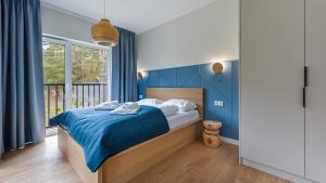 KarwicaApartamenty Sun & Snow Zapach Lasu - Naturalne SPA的一间卧室配有一张蓝色墙壁的床和一扇窗户