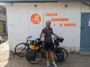 阿里巴格Awaara Backpackers Hostel, Alibag的两辆自行车旁边一个把 ⁇ 指放在一起的人