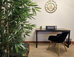 里贝拉Alojamiento GOLDEN SUITE的一张桌子、椅子和墙上的时钟