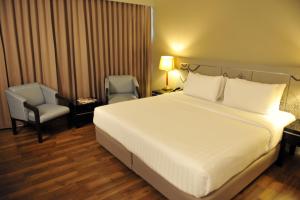 合艾新季节酒店的卧室配有一张白色大床和一把椅子