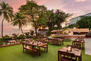 帕纳吉Taj Cidade de Goa Heritage, Goa的一间草地上配有桌椅的餐厅