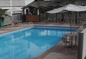 奥韦里Top Rate Hotel的一个带桌子和遮阳伞的大型蓝色游泳池