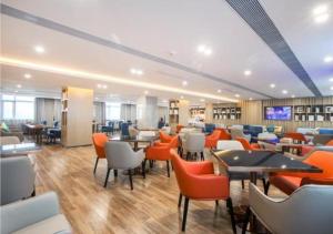 黄花涝Echarm Hotel Wuhan Tianhe Airport Outlets的一间餐厅,房间内设有橙色椅子和桌子