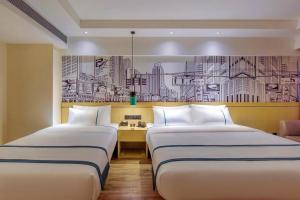 贵阳City Comfort Inn Guiyang Airport Future Ark的两张位于酒店客房的床,墙上挂着画