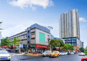 贵阳City Comfort Inn Guiyang Wanda Plaza Jiufu City的一条繁忙的城市街道,汽车停在大楼前