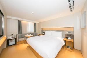 北京JI Hotel Beijing Dazhongsi的卧室配有一张白色的大床和一张沙发。