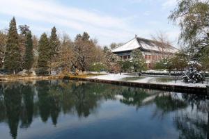 北京JI Hotel Beijing Dazhongsi的建筑前的一座建筑和一座池塘