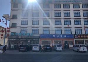 City Comfort Inn Lhasa Gongga County Gongga Airport的一座大型建筑,前面有汽车停放
