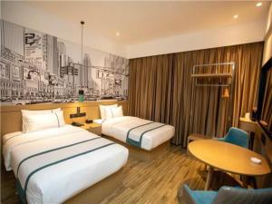 江都City Comfort Inn Yangzhou Jiangdu North Limin Road的酒店客房设有两张床和一张桌子。