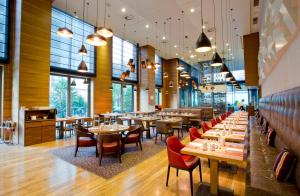 萨格勒布萨格勒布希尔顿逸林酒店的餐厅设有木桌、椅子和窗户。