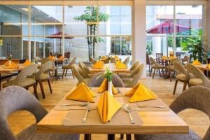 蒂米卡Horison Hotel Ultima Timika的餐厅设有木桌、椅子和黄色餐巾