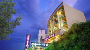 江陵市Gangneung Four Season Hotel and Pension的前面有 ⁇ 虹灯标志的高楼