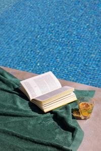 马拉加Palacio Solecio, a Small Luxury Hotel of the World的坐在游泳池旁桌子上的书
