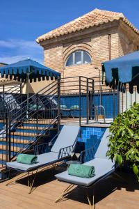 马拉加Palacio Solecio, a Small Luxury Hotel of the World的一个带2把躺椅和遮阳伞的游泳池