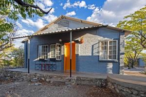 奥考奎约Etosha Safari Camp, Etosha National Park, Namibia的蓝色的小房子,有橙色的门