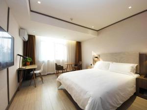 合肥Hanting Hotel Hefei Baoye Dongcheng Plaza的卧室配有一张白色大床和一张书桌