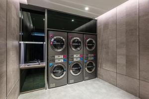 苏州Hanting Hotel Suzhou Guanqian Street Center的洗衣房配有4台洗衣机和水槽