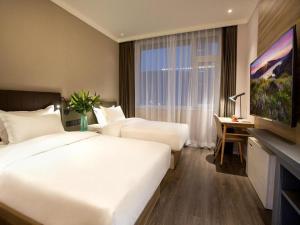 洪家楼Hanting Premium Hotel Jinan Shandong University Central Campus的酒店客房设有两张床和窗户。